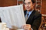 Chine, homme d'affaires de lecture de journal de table de café, gros plan