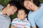 Couple with son (7-9) lying on grass, portrait, elevated view