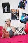 Teenage girl (16-17) sitting on bed, listening to music