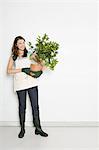 Portrait of woman holding potted orange tree