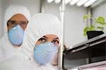 Workers in protective masks and suits in laboratory, portrait