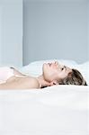 Profil de jeune femme en sous-vêtements, allongée sur le lit, gros plan