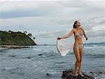 Young Woman Standing on Rock at Beach