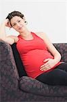 Pregnant woman sitting on sofa, portrait