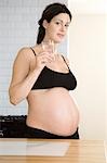 Pregnant woman drinking water in kitchen, portrait