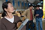 Asian woman making notes in distribution warehouse