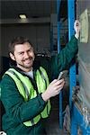 Cheerful man using calculator in factory