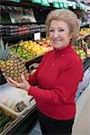 Haute femme tenant des ananas en supermarché