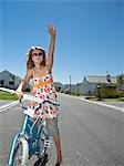 South Africa, Cape Town, girl standing on street with  bicycle and waving