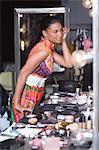 Woman applies makeup in dressing room mirror