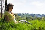 Femme enceinte assise sur l'herbe