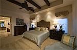 Silk bed cover on double bed in Palm Spring bedroom with beamed ceiling