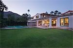 Lawn and swimming pool with lit exterior of Palm Springs home exterior