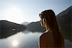 Blonde woman looks out across morning sunrise over lake