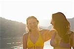 Two friends stand laughing in swimwear at dawn