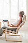 Femme enceinte, assis sur une chaise à l'aide d'ordinateur portable
