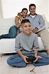 Parents Watching Son Play Video Games in living room, front view