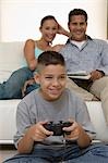 Parents regarder fils jouer de jeux de vidéo dans le salon, vue de face