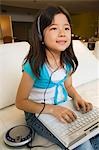 Girl sitting on sofa Using Laptop and Listening to Music