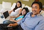 Family Relaxing on sofa in Living Room, daughter with Laptop, portrait