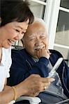 Senior couple using mobile phone, smiling, outdoors