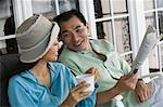 Couple drinking coffee and reading newspaper on porch