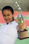 Junges Mädchen auf Tennisplatz hält Trophäe, Fokus auf trophy