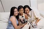 Mother and Daughters on sofa looking at Video Camera screen