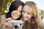 Deux jeunes femmes regardant des photos sur l'appareil photo numérique dans la Cour arrière, vue de face