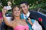 Well-dressed teenage couple taking picture outside car