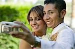Well-dressed teenage couple taking photograph outside