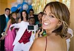 Well-dressed teenager girl video taping friends at school dance
