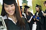 Graduate using Cell Phone outside with others behind