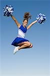 Smiling Cheerleader jumping in mid-air, (portrait), (low angle view)