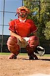 Baseball catcher crouching on baseball field, giving hand signals