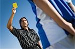Referee holding up yellow card, portrait, low angle view