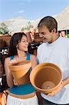 Young couple holding flower pots in outdoors garden centre