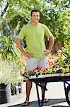 Young man standing in garden centre, (portrait)