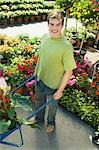Young man with pushcart in garden centre, (portrait), (elevated view)