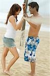 Young couple on Beach standing with Volleyball Net between Them, side view