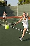 Tennis Player Reaching to hit tennis ball on tennis court