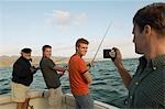 Man photographing family fishing on boat