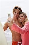 Young couple taking picture with cell phone on beach