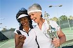 Two female tennis players with award cup