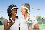 Two female tennis players with award cup