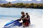 Young couple riding jetski on lake, portrait