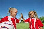 Two girl soccer players (7-9 years) doing 'high five' on soccer field