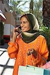 Portrait of muslim woman with shopping bags talking on mobile