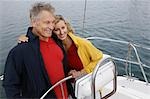 Couple at helm of sailboat, smiling, elevated view