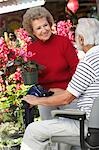 Senior woman talking with elderly man on motor scooter in garden center